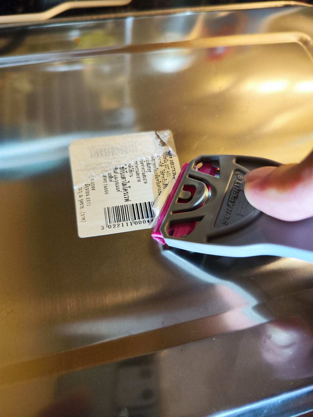 Plastic razor scraper removing a sticker from a magazine cover SRT33GPO