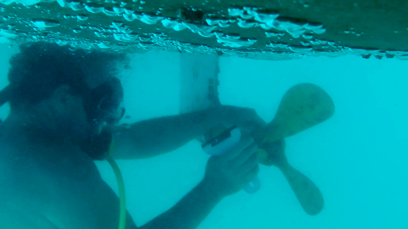 Diver using a non-scratch scraper on a boat propeller underwater